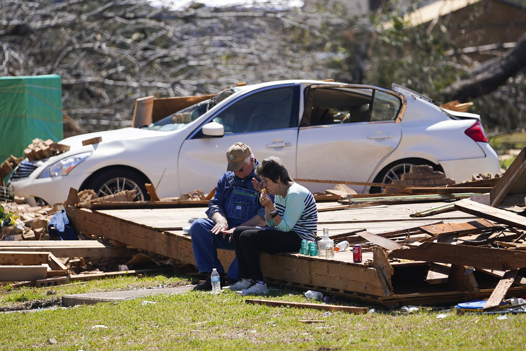 Charles Shields, left, sits with friend Robbie Diffey on the roof of Diffey's garage after a tornado destroyed her home