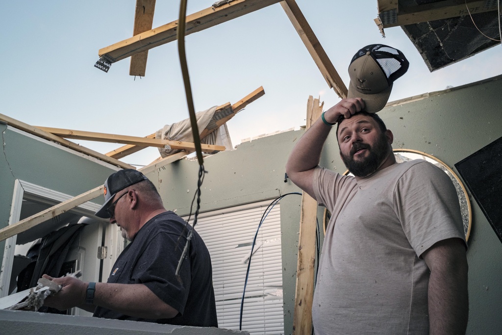 Jacob Dilks, right, looks over storm damage to his home in Hills, Iowa 