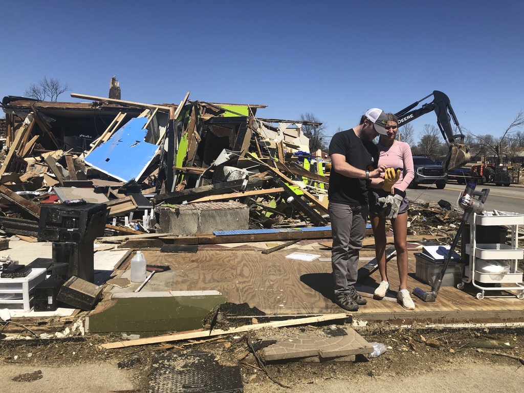 Two people stand in front of a destroyed business in Wynne, Ark.