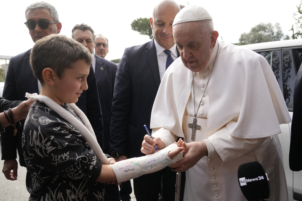 Pope Francis autographs the plaster cast of a child as he leaves the Agostino Gemelli University Hospital in Rome,
