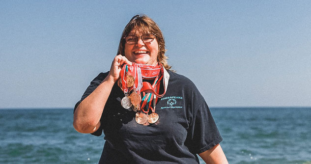 Woman comes out of ocean with lots of medals around her neck