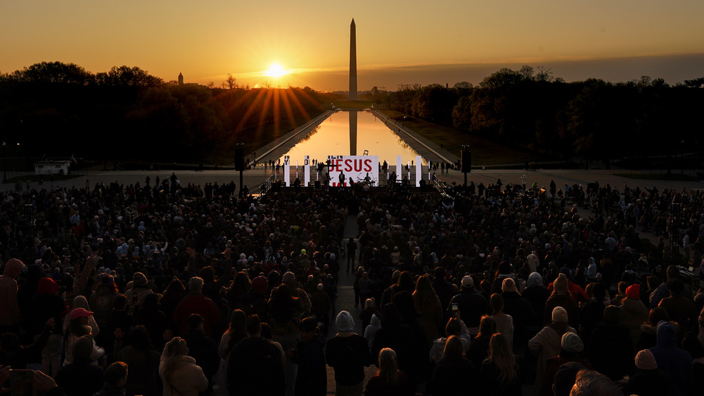 "Jesus" is displayed on a large monitor and worship songs are played on stage as people gather for the "Easter Sunrise Service" at the Lincoln Memorial