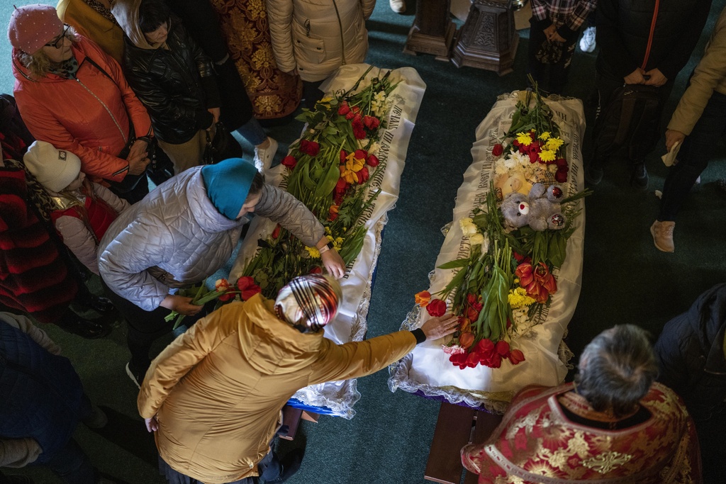 Mourners place flowers on the coffins of Sofia Shulha, 11, and Pysarev Kiriusha, 17, during a funeral in Uman, central Ukraine