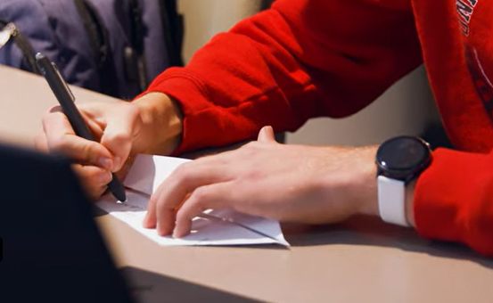 Student writes note on paper airplane