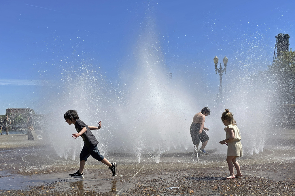 Children play in a fountain to cool off in downtown Portland, Ore., Friday, May 12, 2023.