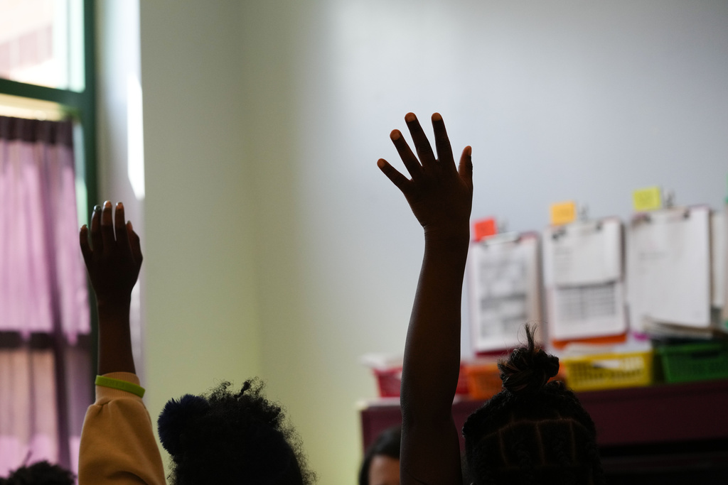 Third graders raise their hands during class at Schaumburg Elementary