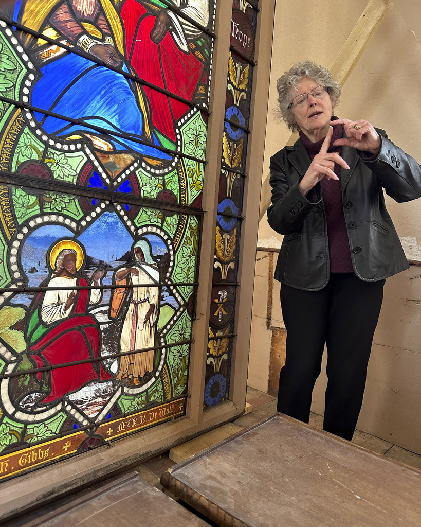 Holy Cross professor and stained-glass expert Virginia Raguin speaks to a group of middle school students while standing near a nearly 150-year-old stained-glass window that depicts Christ speaking to a Samaritan woman, in the now-closed St. Mark