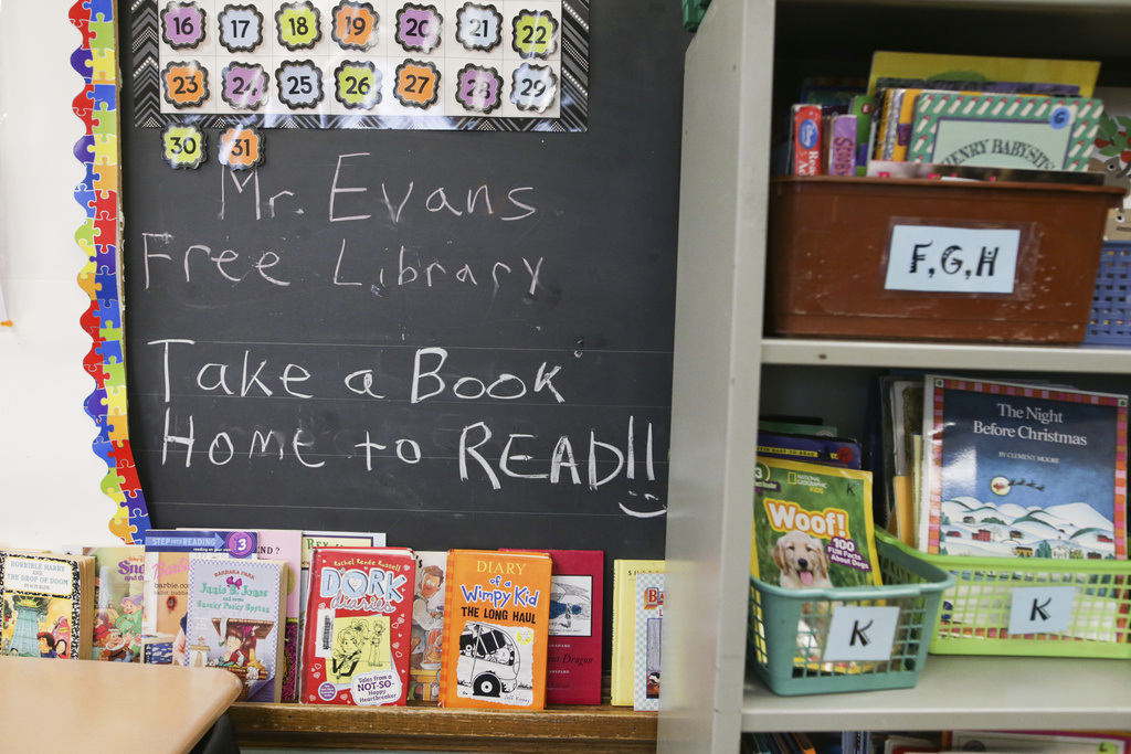 Books are displayed on a free library shelf inside the classroom of Richard Evans