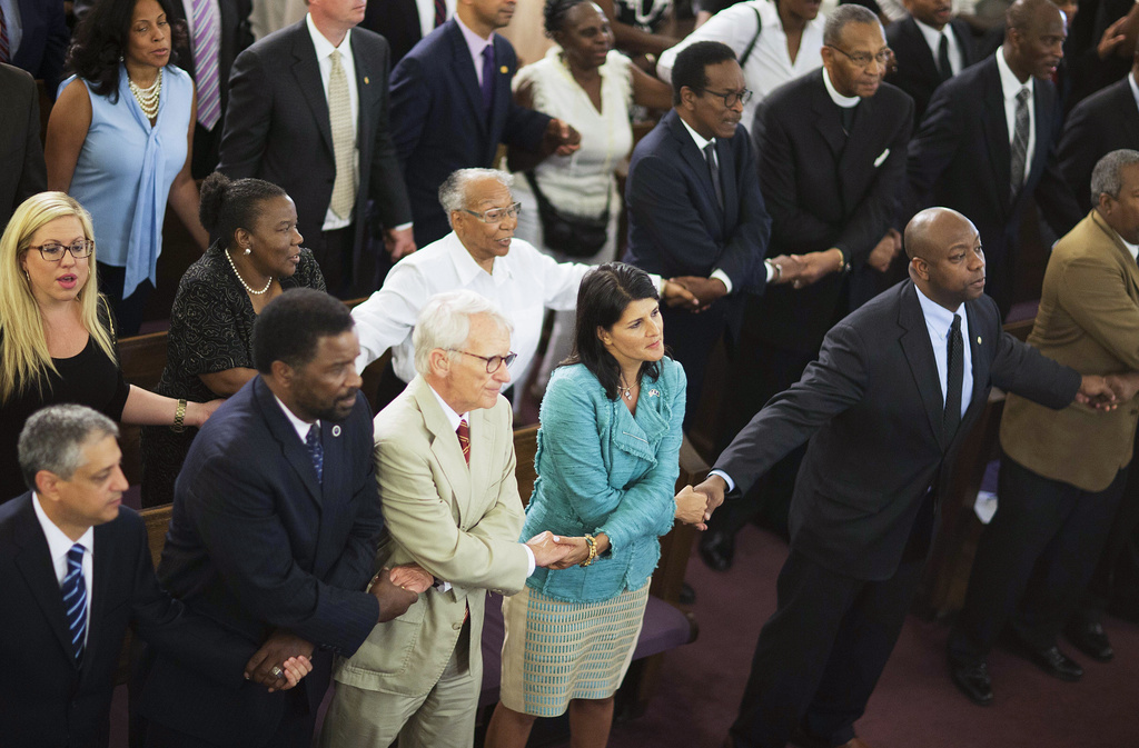 South Carolina Gov. Nikki Haley, center right, joins hands with Charleston Mayor Joseph Riley, left, and Sen. Tim Scott, R-S.C., right, at a memorial service at Morris Brown AME Church for the people killed during a prayer meeting inside the historic black church in Charleston, S.C., June 18, 2015