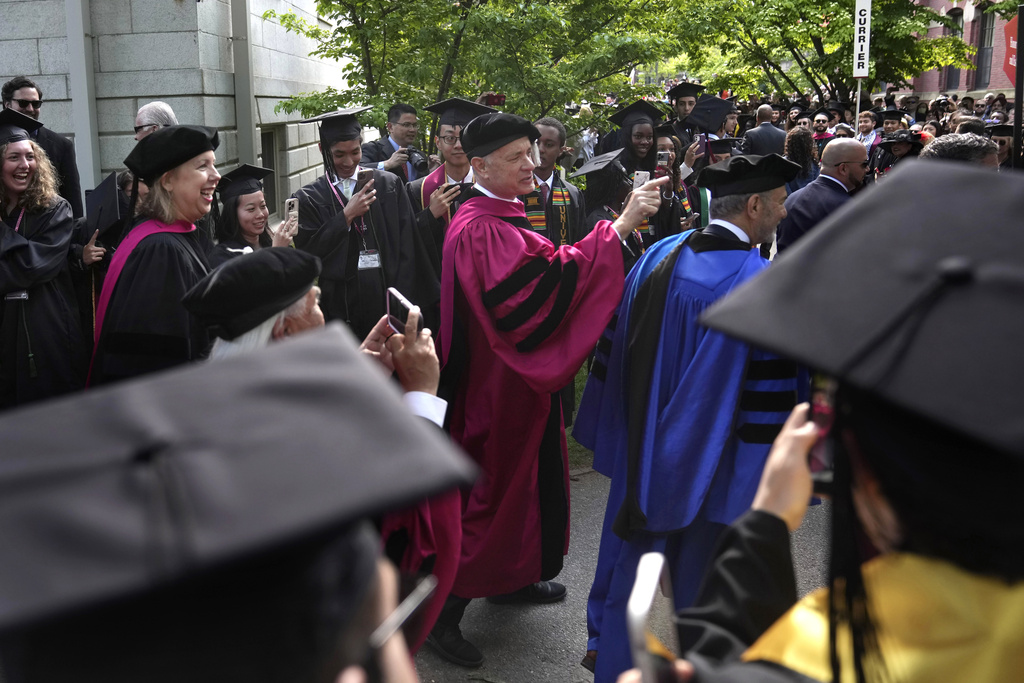 Actor Tom Hanks, center, greets people as he walks in a procession though Harvard Yard 