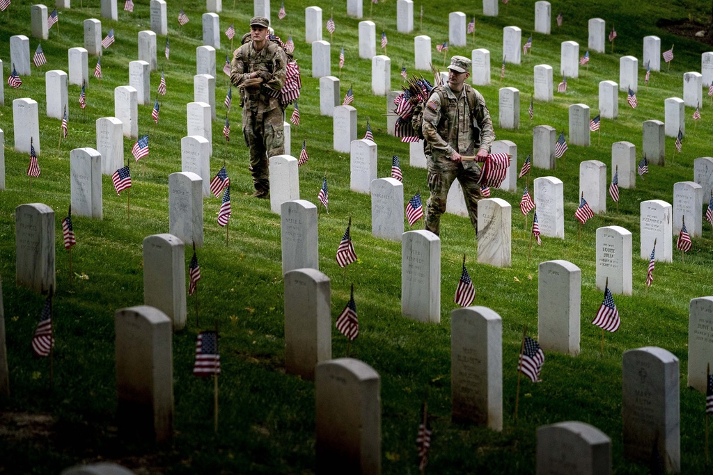 Members of the 3rd U.S. Infantry Regiment also known as The Old Guard place flags in front of each headstone for "Flags-In" at Arlington National Cemetery 