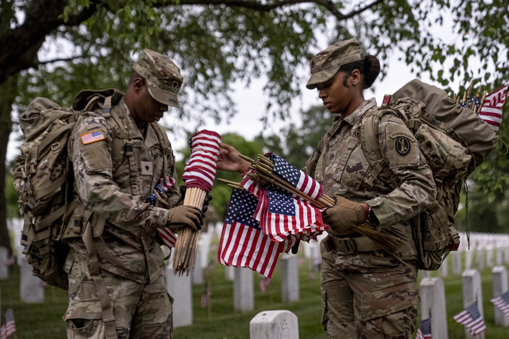 Members of the 3rd U.S. Infantry Regiment also known as The Old Guard, place flags in front of each headstone for "Flags-In" at sunrise at Arlington National Cemetery in Arlington, Thursday, May 25, 2023, to honor the Nation's fallen military heroes ahead of Memorial Day