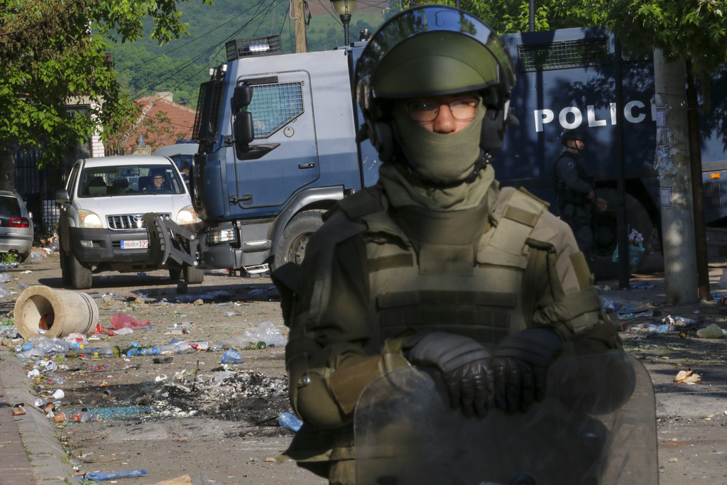 KFOR soldiers, front, and Kosovo police officers guard a municipal building after yesterday