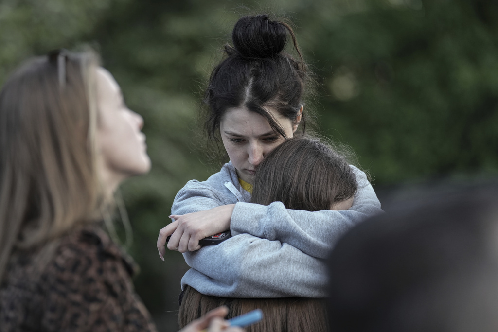 Evacuated residents hug outside of their multi-story apartment building which was damaged during Russian attack in Kyiv