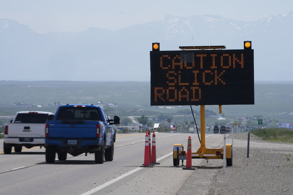 A highway sign warning, "Caution Slick Road," is shown, Saturday, June 17, 2023, in Spring Creek, Nev. State transportation officials have put up signs on highways warning drivers of greasy roads.