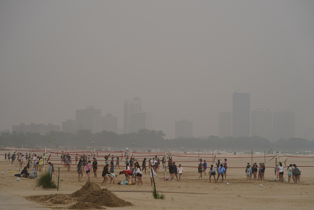 Children participate in a summer camp on Montrose Beach as buildings behind the shore are blanketed in haze