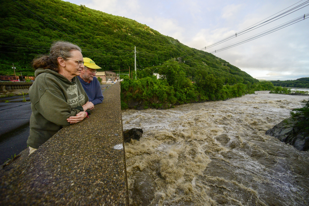 People stand on the Vilas Bridge, in Bellows Falls, Rockingham, Vt., to watch the water from the Connecticut River 