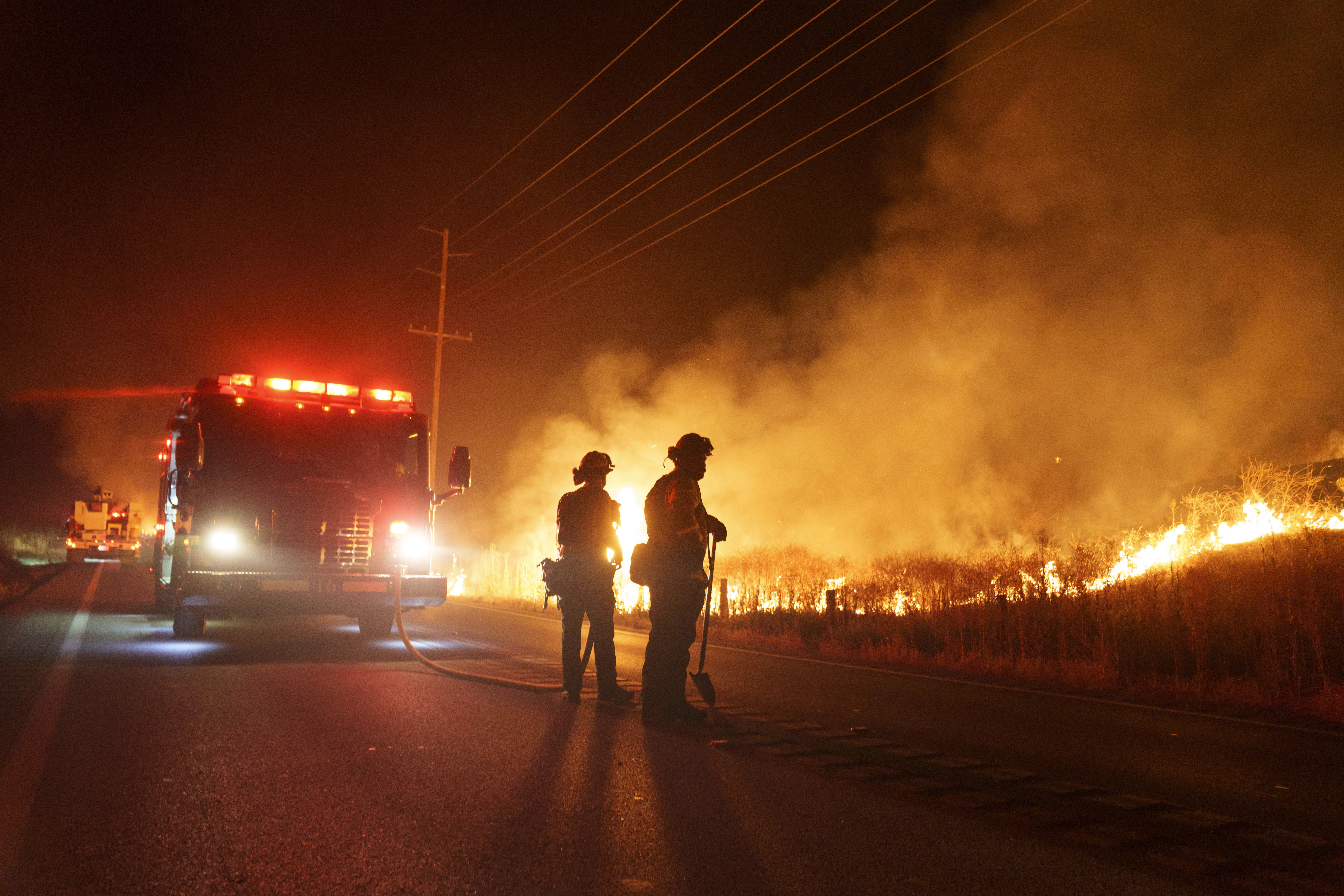 Firefighters monitor as flames consume brush along Gilman Springs Road during the Rabbit Fire late Friday, July 14, 2023, in Moreno Valley, Calif.