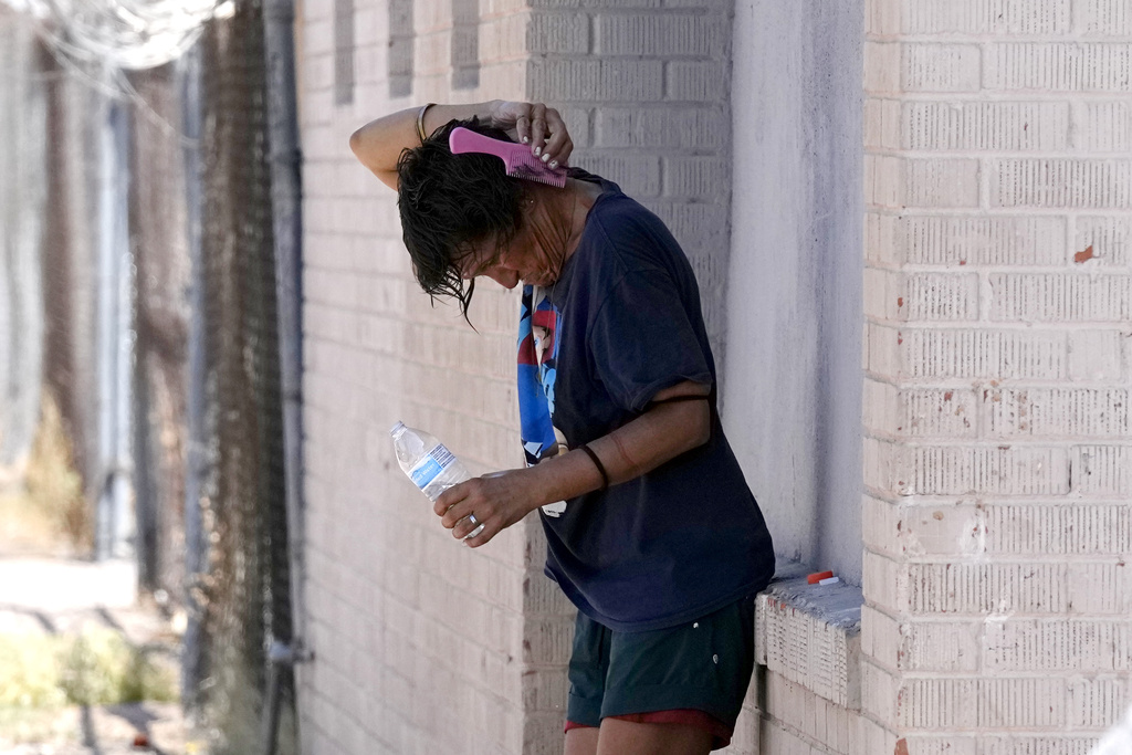 A person tries to cool off in the shade as temperatures are expected to hit 116-degrees Fahrenheit in Phoenix