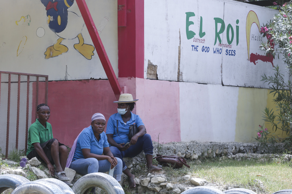 Staff sit in front of a school funded by El Roi Haiti in the Cite Soleil neighborhood of Port-au-Prince, Haiti