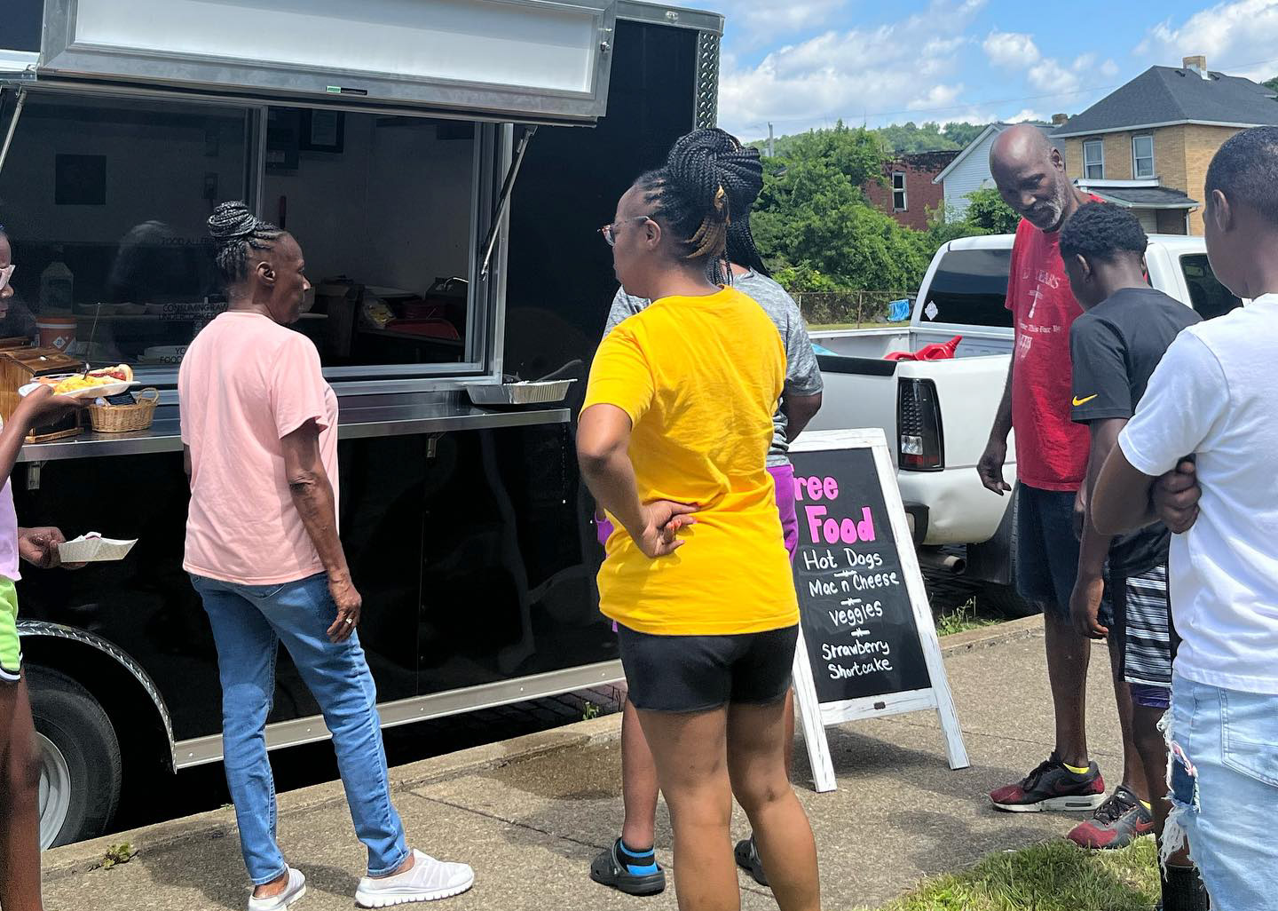 Men, women and teens waiting in line for free food at the Little Free Food Truck