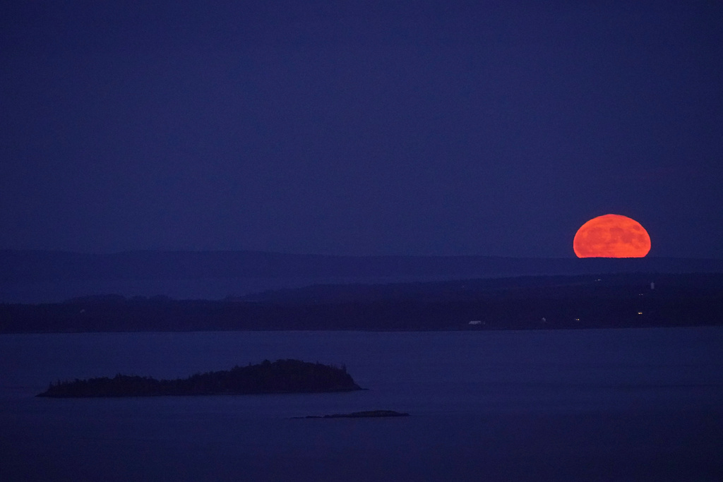 The supermoon rises behind Isle Au Haut in the distance, and North Haven Island