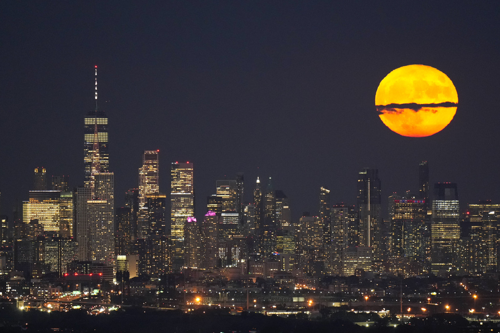 The moon rises through clouds over the skyline of lower Manhattan in this view from West Orange, N.J.