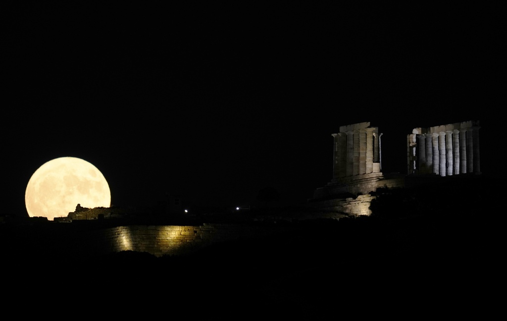 The full moon rises behind the ancient temple of Poseidon at Cape Sounion in Greece