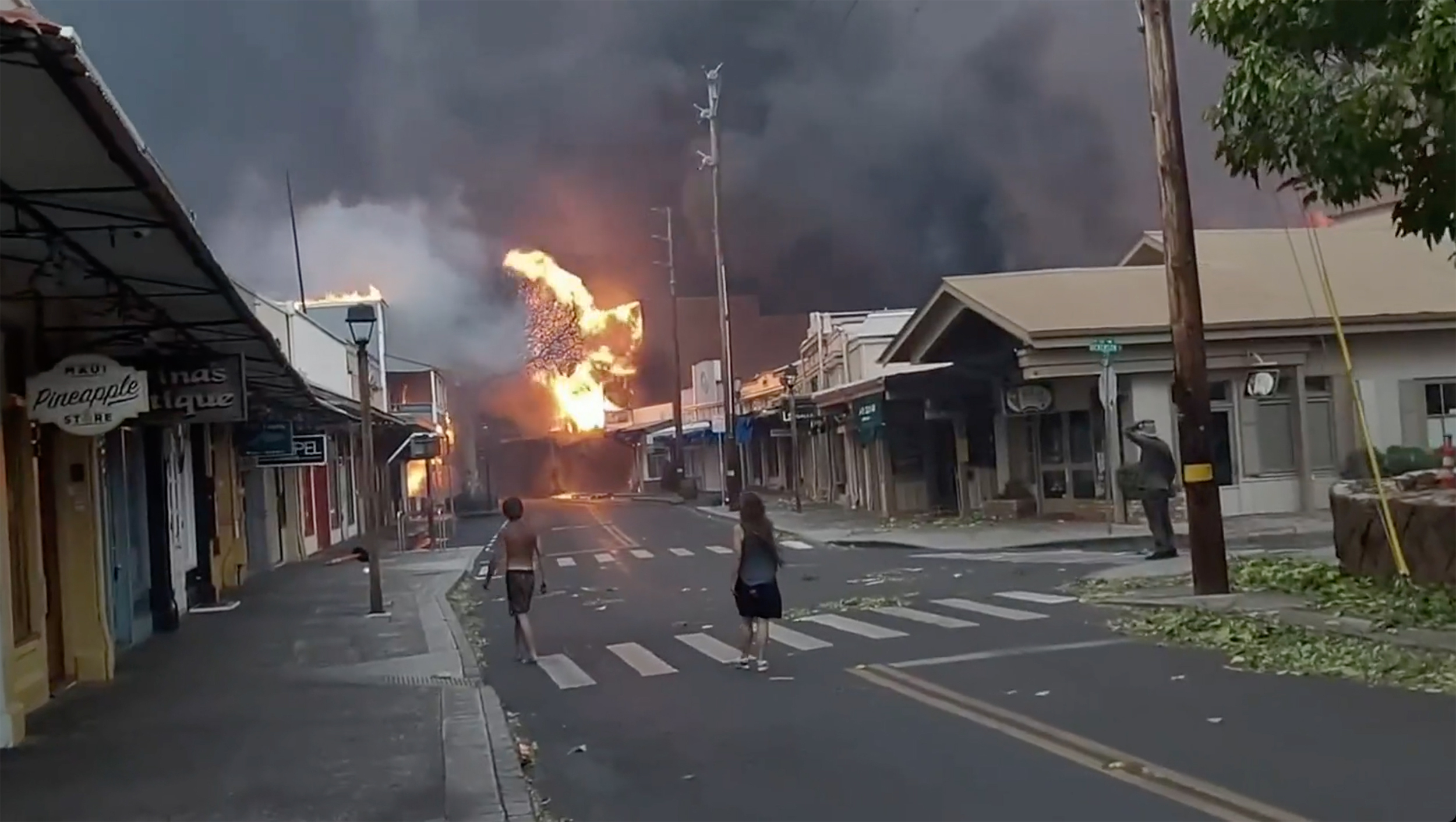 People watch as smoke and flames fill the air from raging wildfires on Front Street in downtown Lahaina, Maui