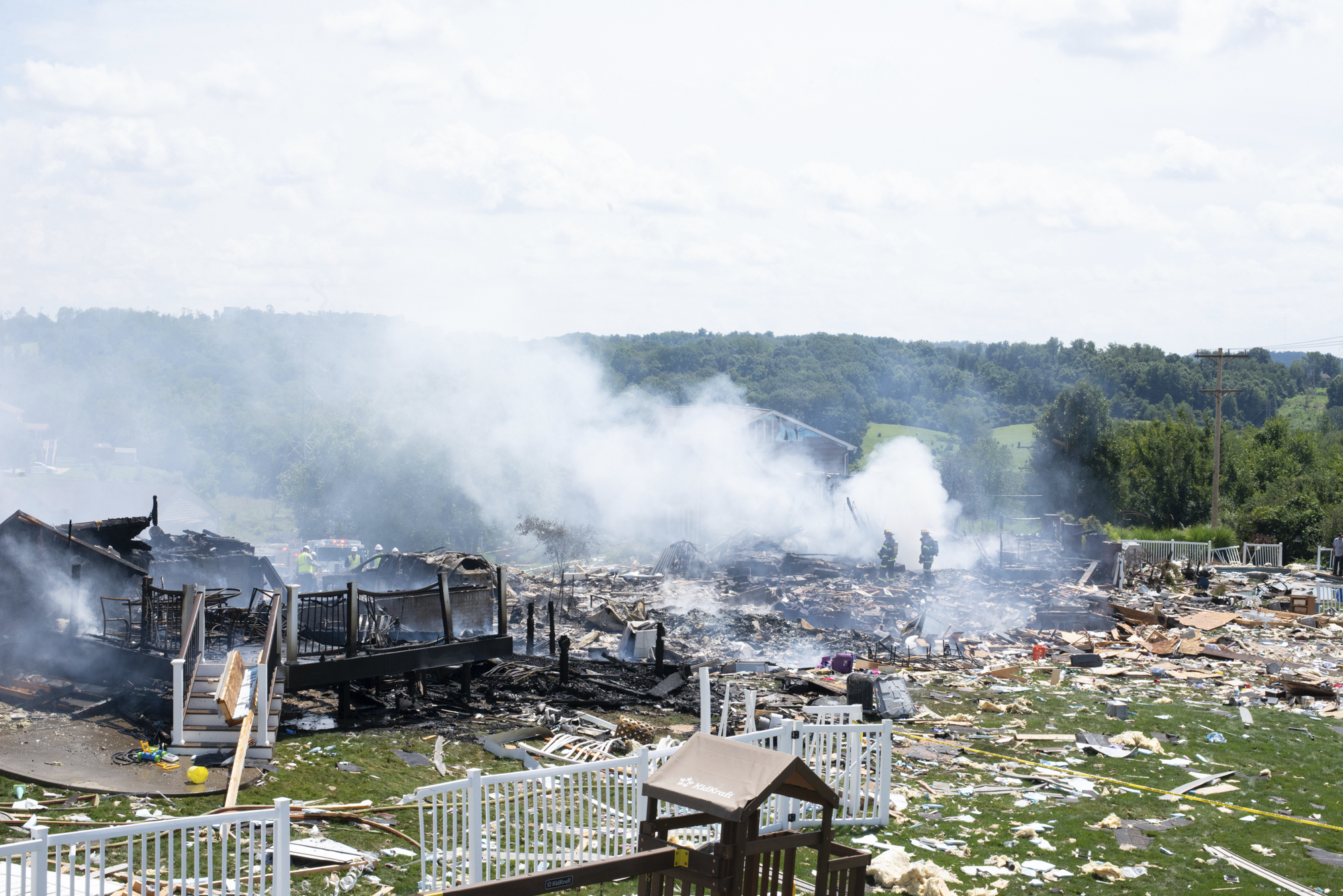 Two firefighters stand on the debris around the smoldering wreckage of the the three houses that exploded near Rustic Ridge Drive and Brookside Drive in Plum, Pa., on Saturday, Aug. 12, 2023.