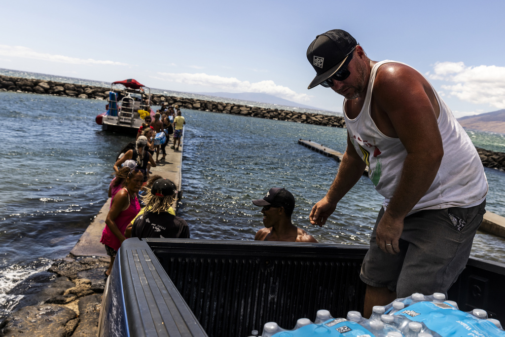 Pauwela Store owner Justin Kriegh, right, unloads cases of water as a chain of volunteers load supplies onto a boat for West Maui at the Kihei boat landing