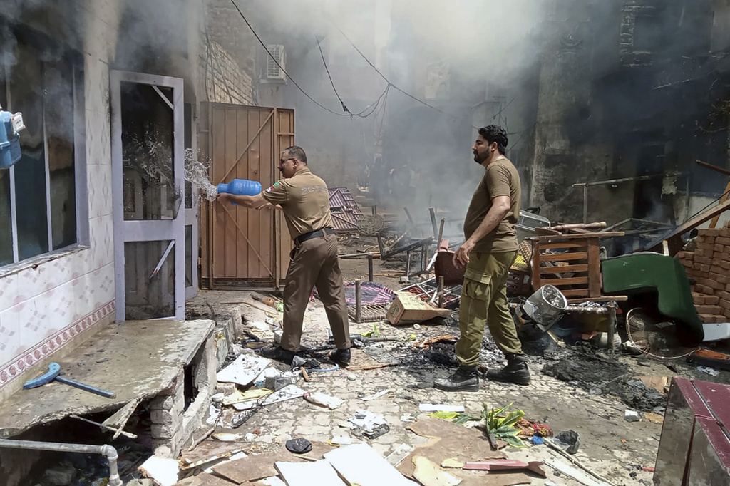 Police officer pours water into a burning house at a Christian neighborhood following an angry mob attack in Jaranwala near Faisalabad, Pakistan