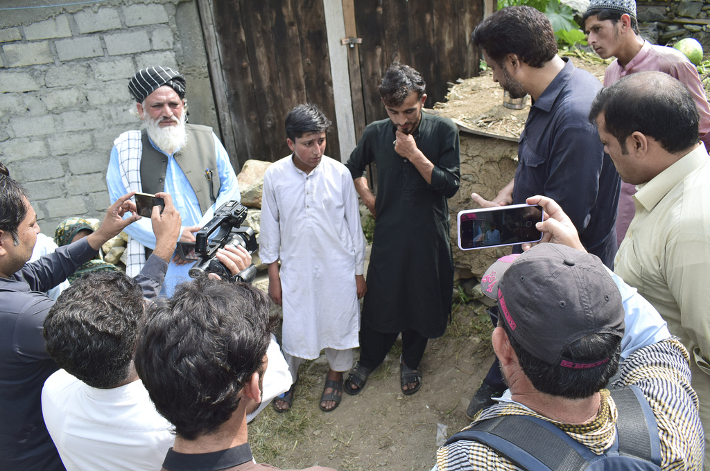 Gul Faraz, center right, and Rizwan Ullah, center left, survivors of cable car incident, talk to members of media, at near the incident site, in Pashto village, a mountainous area of Battagram district in Pakistan