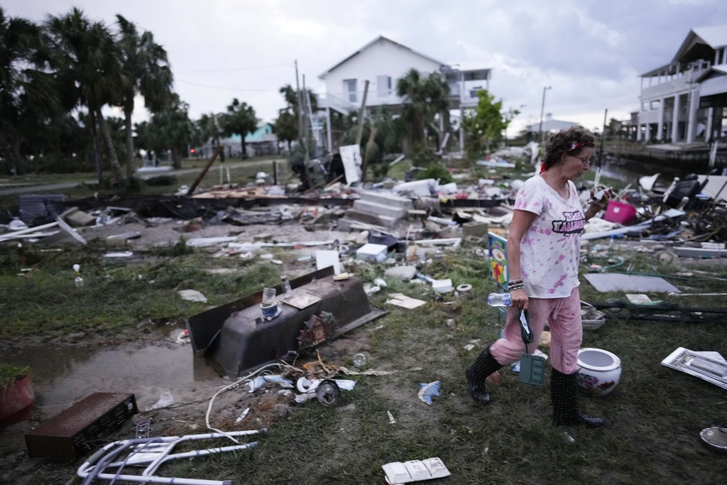 Jewell Baggett walks amidst debris strewn across the yard where her mother’s home had stood