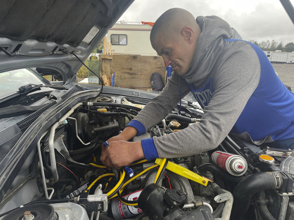 Scott Gibson, a resident of a homeless camp, works on a car 