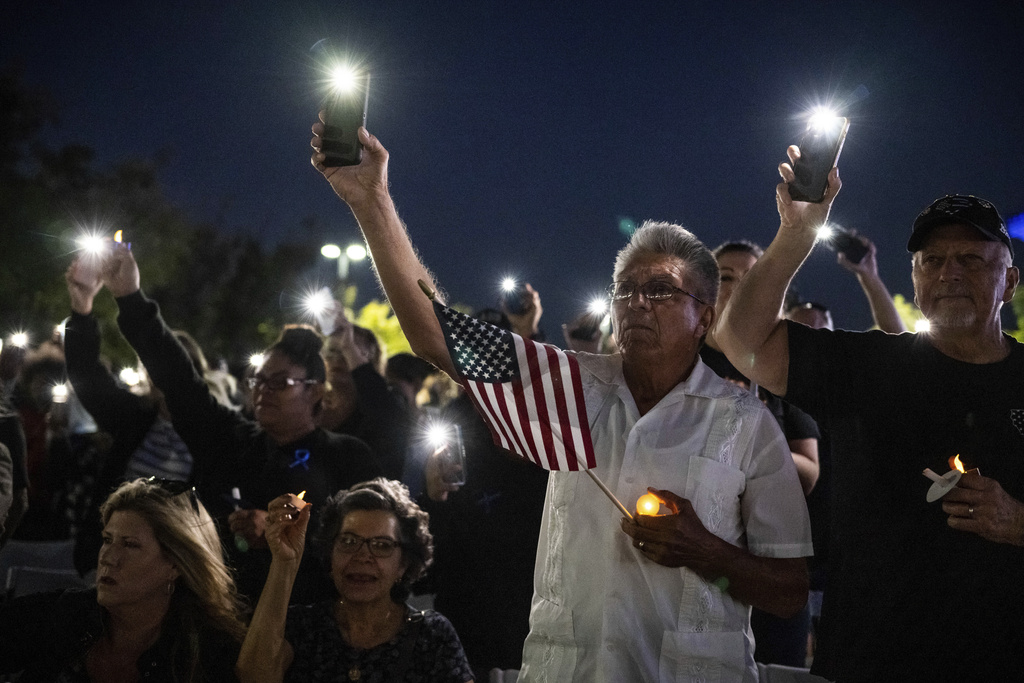 Miguel Ruiz, center, and his wife, Sara, seated, attend a vigil in Palmdale, Calif., for Los Angeles County Sheriff's Deputy Ryan Clinkunbroomer at the Palmdale Sheriff's Station