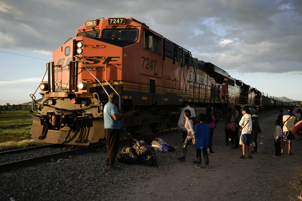 Migrants watch a train go past as they wait along the train tracks hoping to board a freight train heading north, one that stops long enough so they can hop on, in Huehuetoca, Mexico