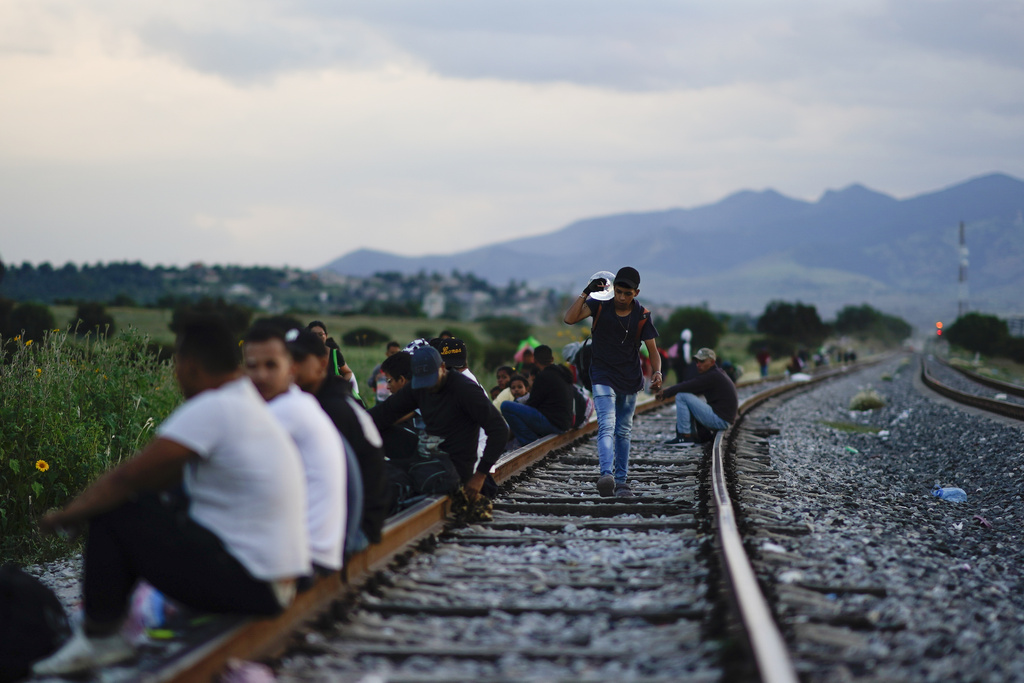 Migrants wait along rail lines hoping to board a freight train heading north, one that stops long enough so they can hop on, in Huehuetoca, Mexico