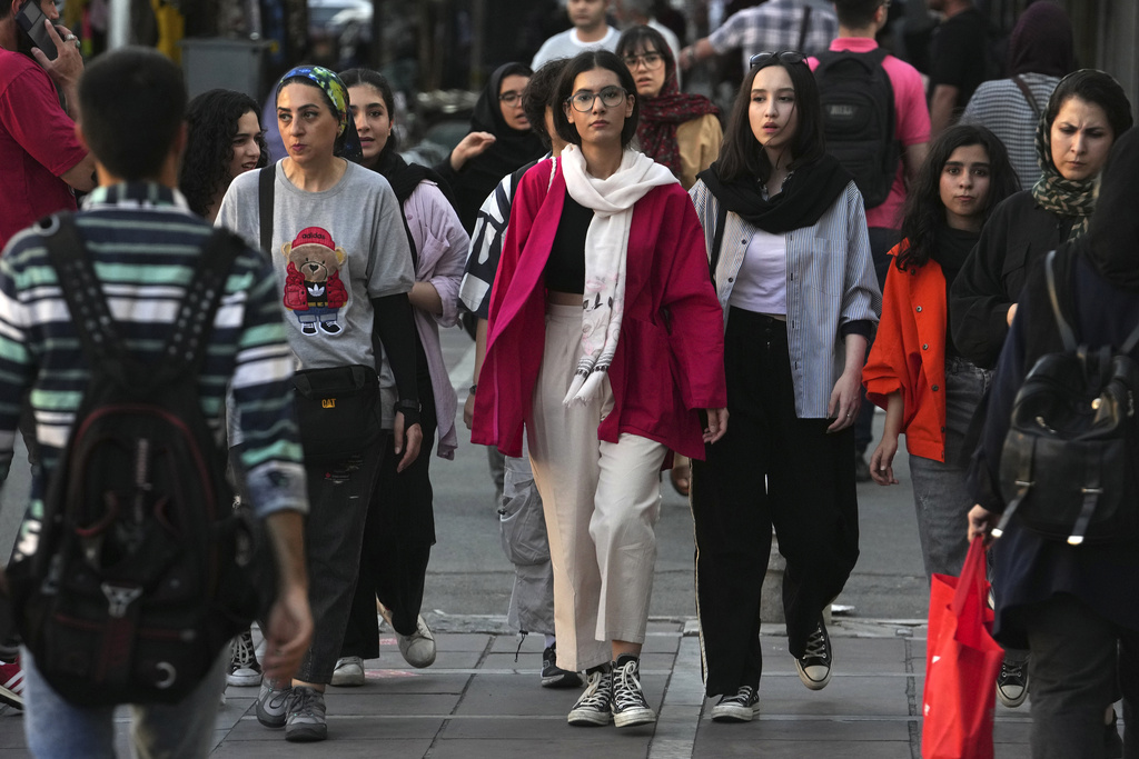 Iranian women, some without wearing their mandatory Islamic headscarves, walk in downtown Tehran, Iran