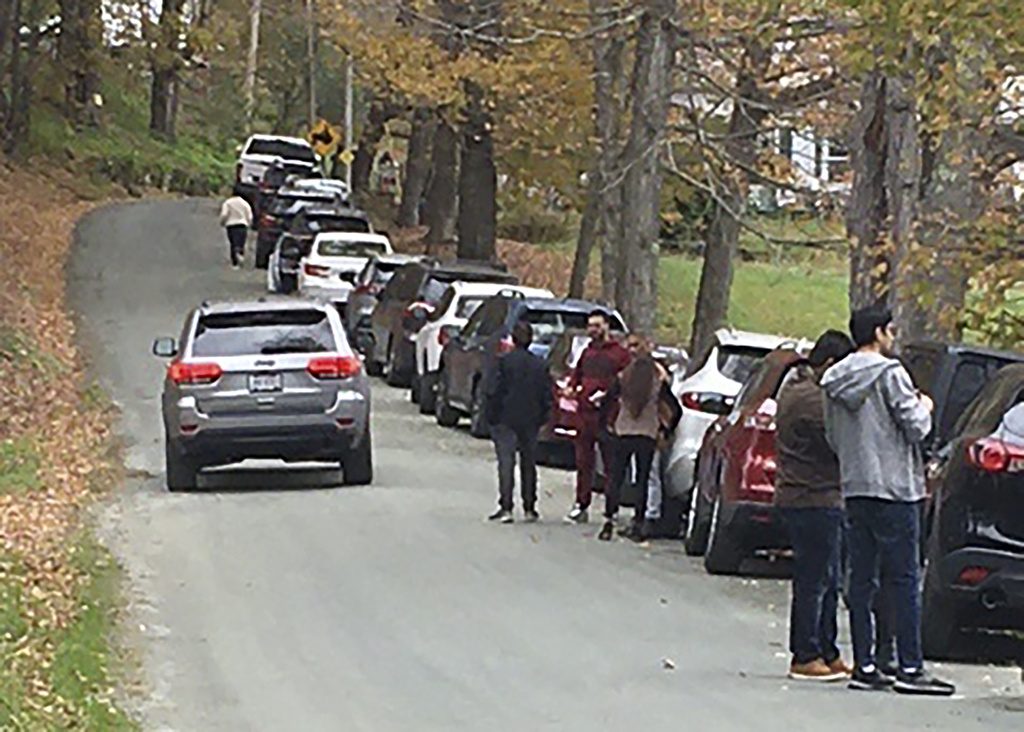 People and cars line a narrow road outside a private property in Pomfret, Vt., that has become a destination for fall foliage viewers, clogging the rural road. 