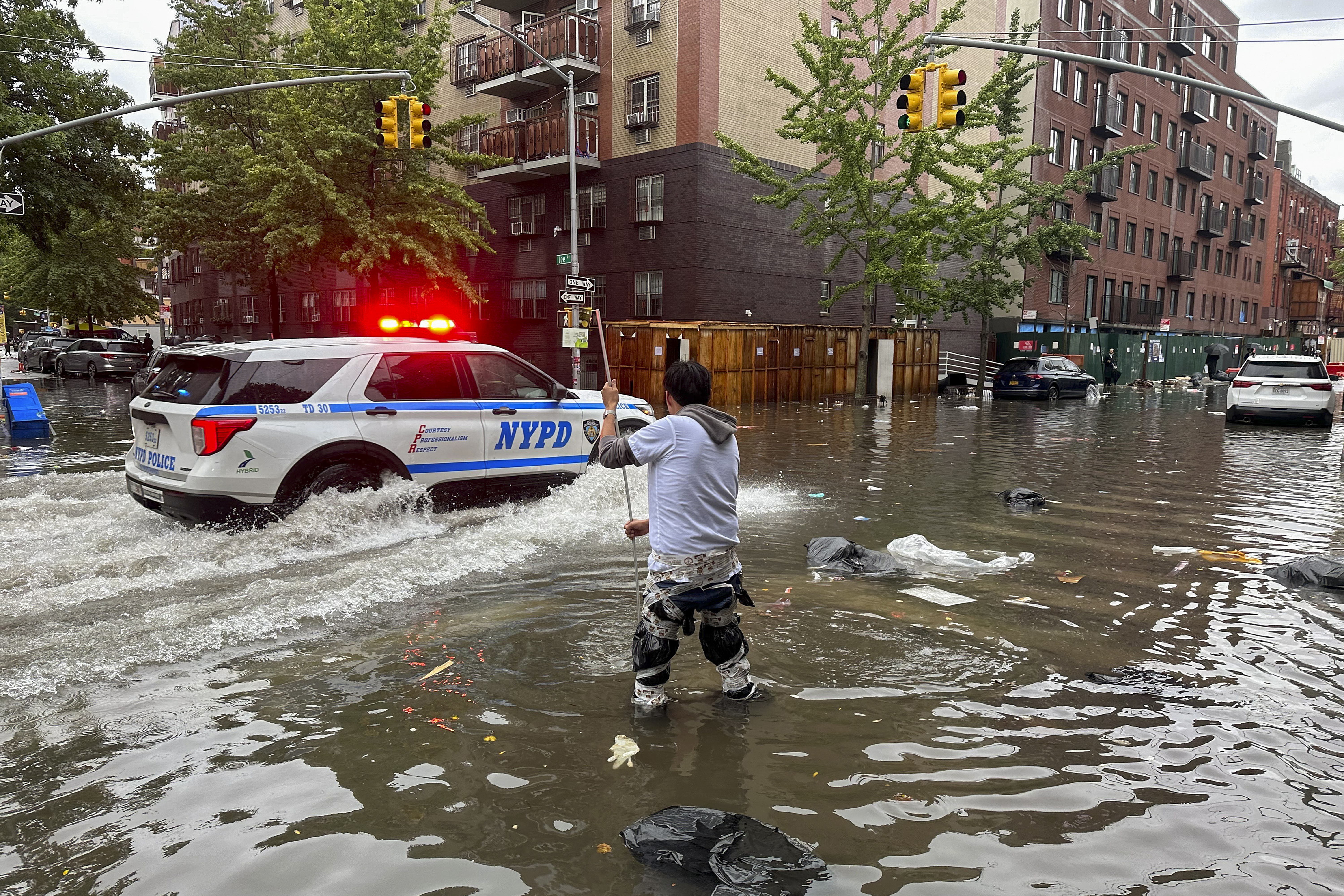 A man works to clear a drain in flood waters, Friday, Sept. 29, 2023, in the Brooklyn borough of New York. A potent rush-hour rainstorm has swamped the New York metropolitan area. The deluge Friday shut down swaths of the subway system, flooded some streets and highways, and cut off access to at least one terminal at LaGuardia Airport.