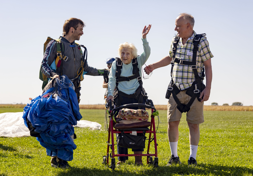 Dorothy Hoffner, 104, waves to the crowd with tandem jumper Derek Baxter, left, and friend Joe Conant