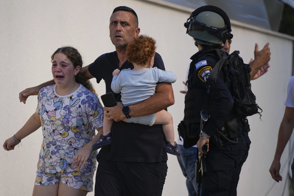 Israeli police officers evacuate a family from a site hit by a rocket fired from the Gaza Strip, in Ashkelon