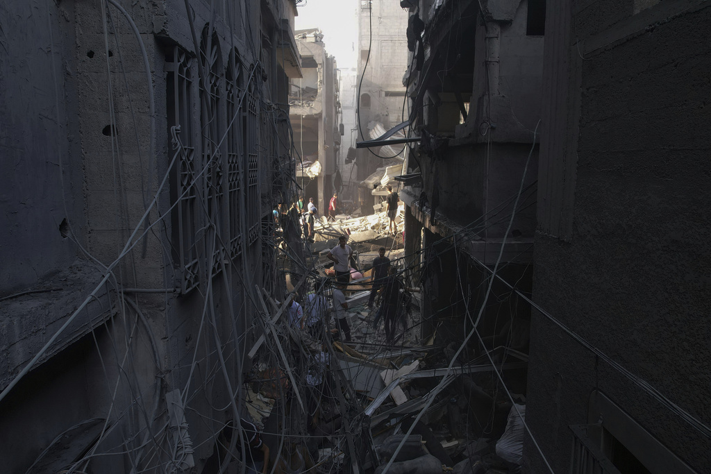 Palestinians inspect the rubble of buildings hit by an Israeli airstrike at Al Shati Refugee Camp 