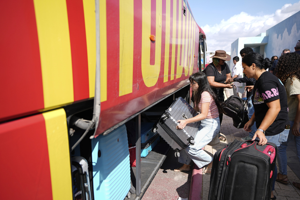 Israelis load their belongings onto a bus as they evacuate from the southern Israeli town of Sderot