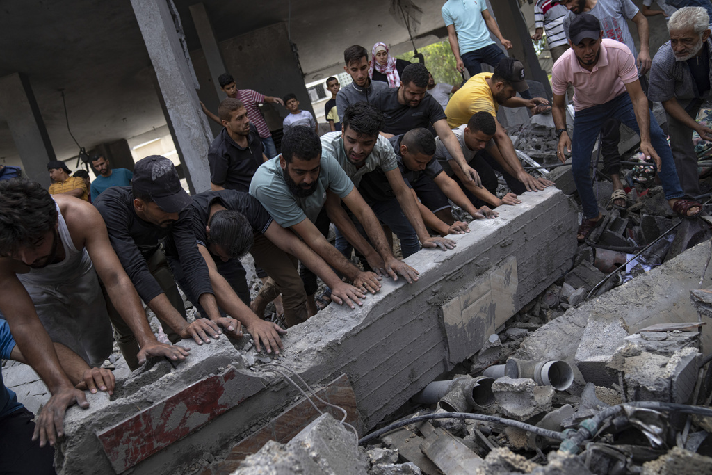 Palestinians look for survivors in a building destroyed in Israeli bombardment in Rafah refugee camp 