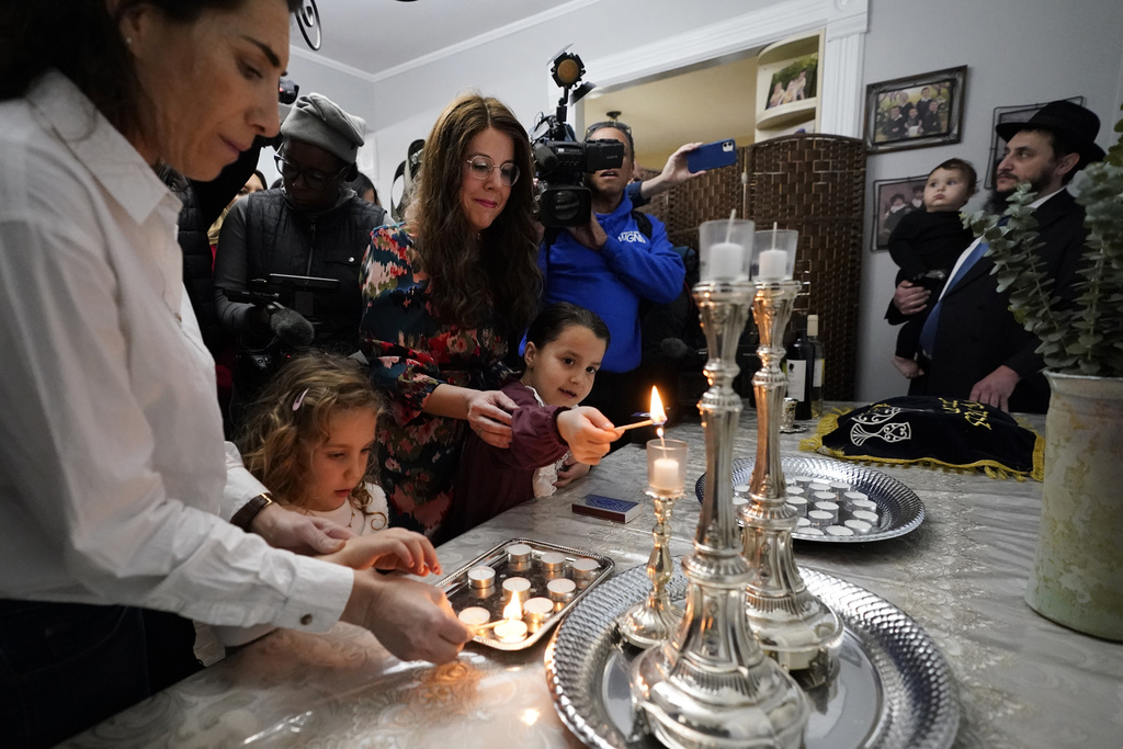 Members of the Chabad of Evanston, Ill., Yehudis Hecht, center, and her daughter Chana, and Maayan Hill, left, and her daughter Emilia, where Judith Raanan attended, light candles to mark the beginning of Shabbat on Friday, Oct. 20