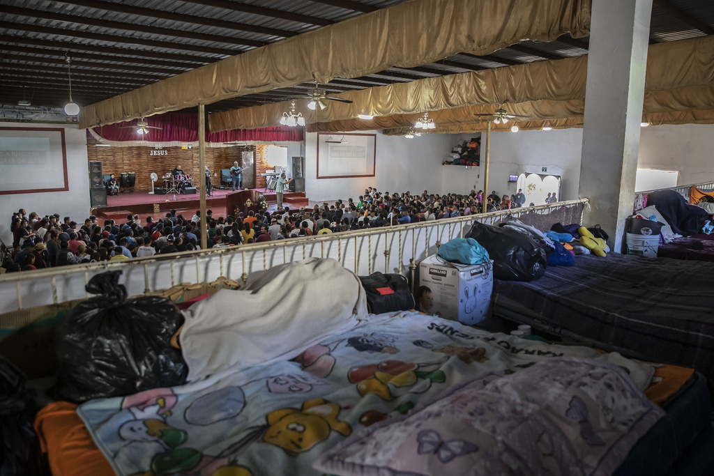 Beds cover an upper floor of the "Embajadores de Jesus" Christian migrant shelter as Mexican migrants, many from Michoacan state, attend a religious service on the bottom floor in Tijuana