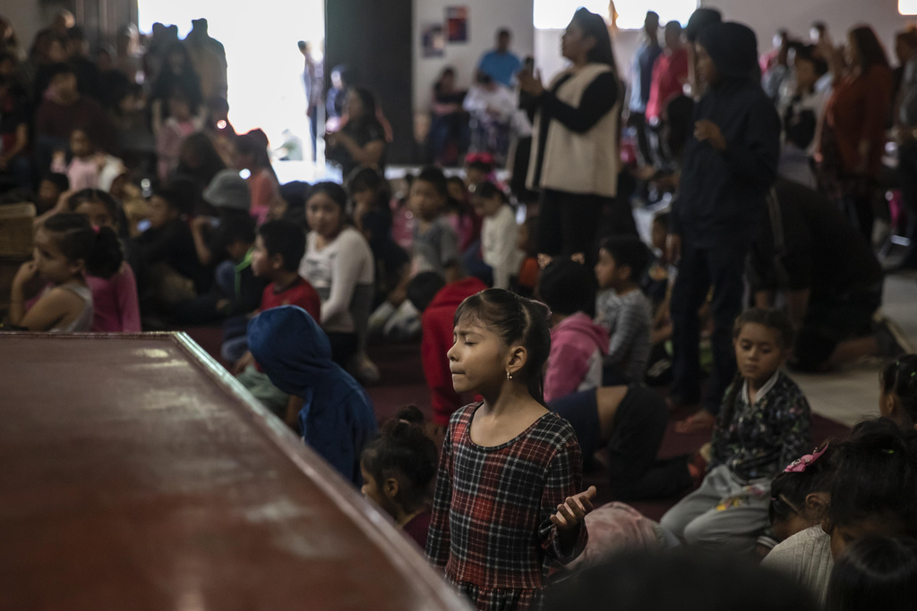 A young migrant prays during a service at the "Embajadores de Jesus" Christian migrant shelter in Tijuana
