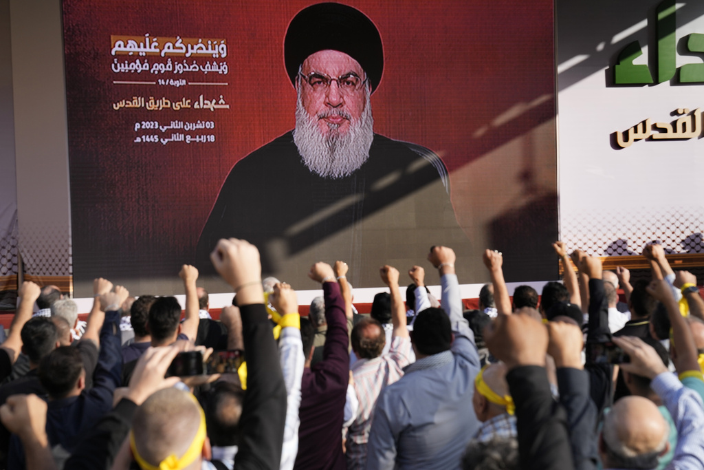 Supporters of the Iranian-backed Hezbollah group raise their fists and cheer as Hezbollah leader Sayyed Hassan Nasrallah appears via a video link, during a rally to commemorate Hezbollah fighters who were killed in South Lebanon